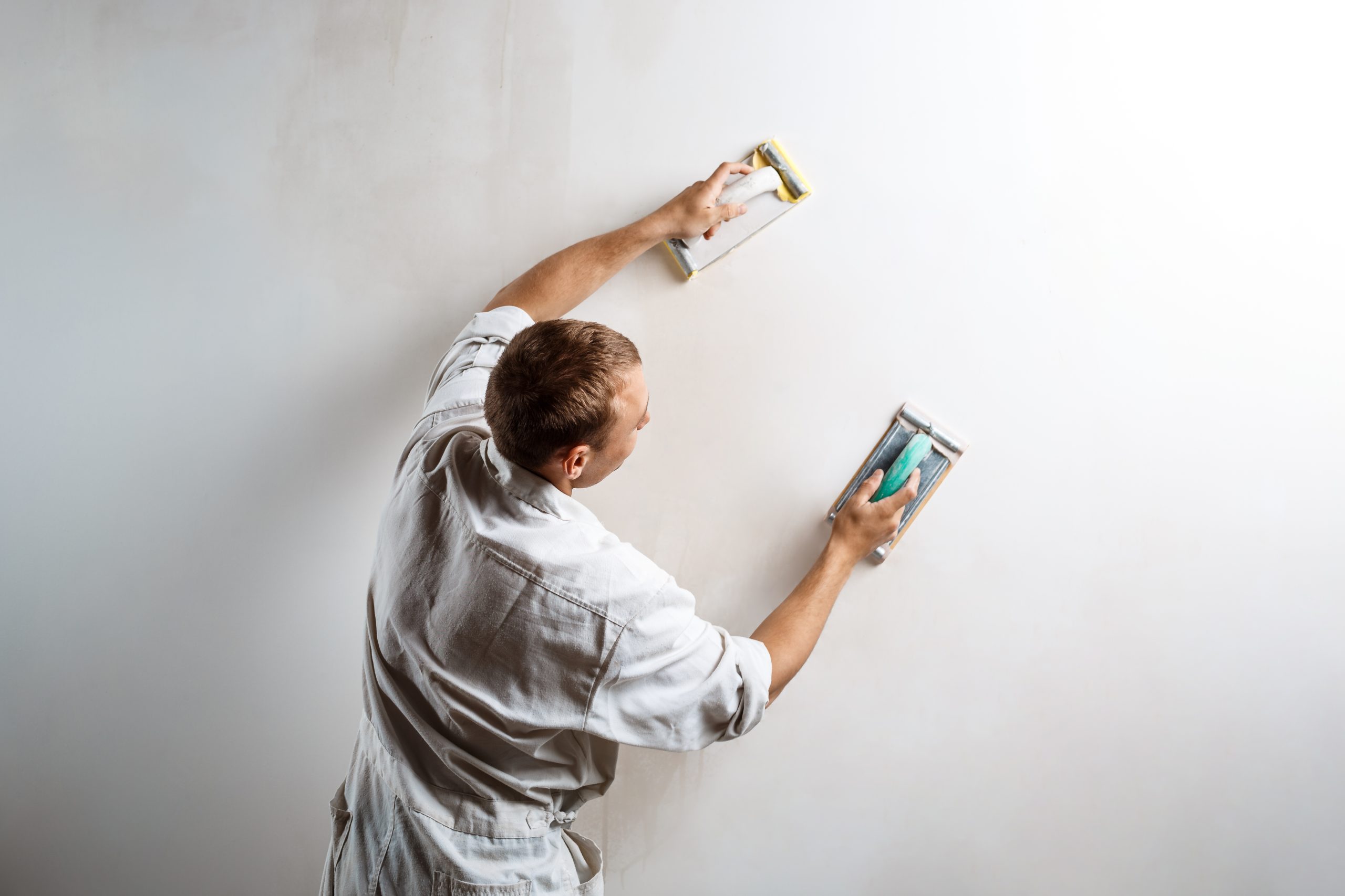 worker-grinding-white-wall-with-sandpaper-stucco home exterior-scaled